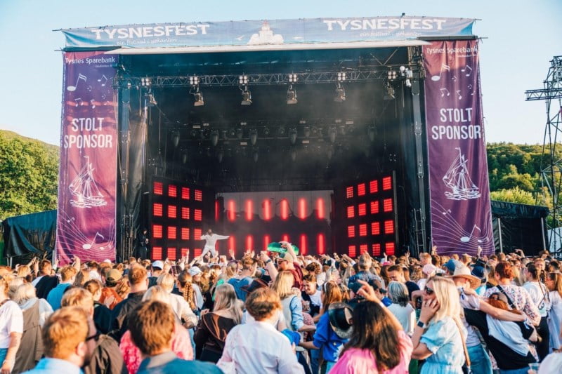Stor festivalscene med artist, mange hundre folk i forgrunnen