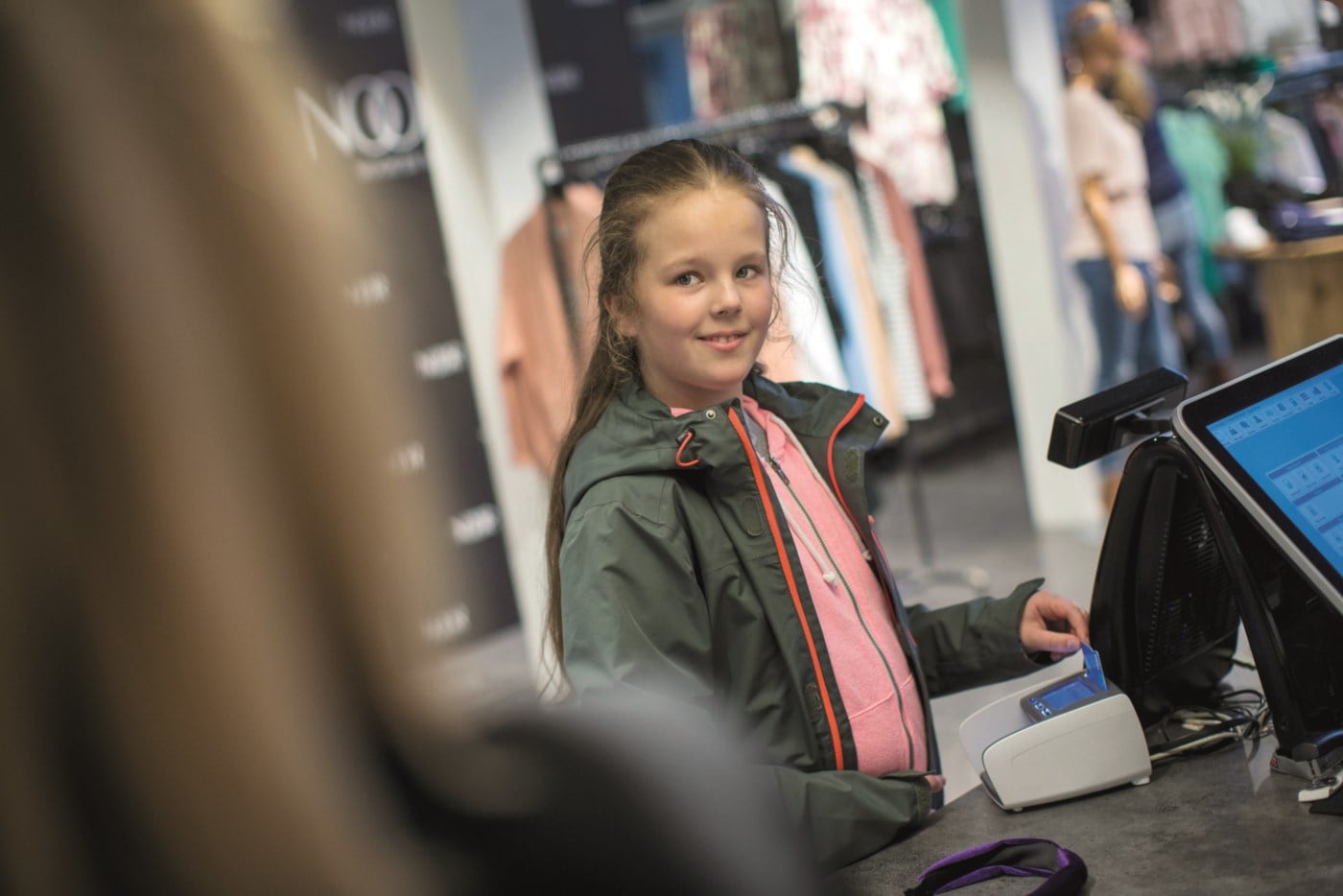 En unge jente bruker bankkortet sitt i en butikk